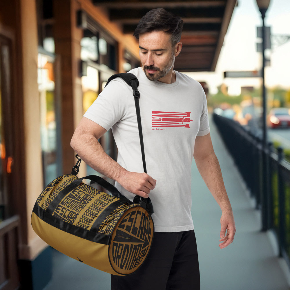 Man holding a yellow duffel bag with a brand logo, standing in an outdoor setting.