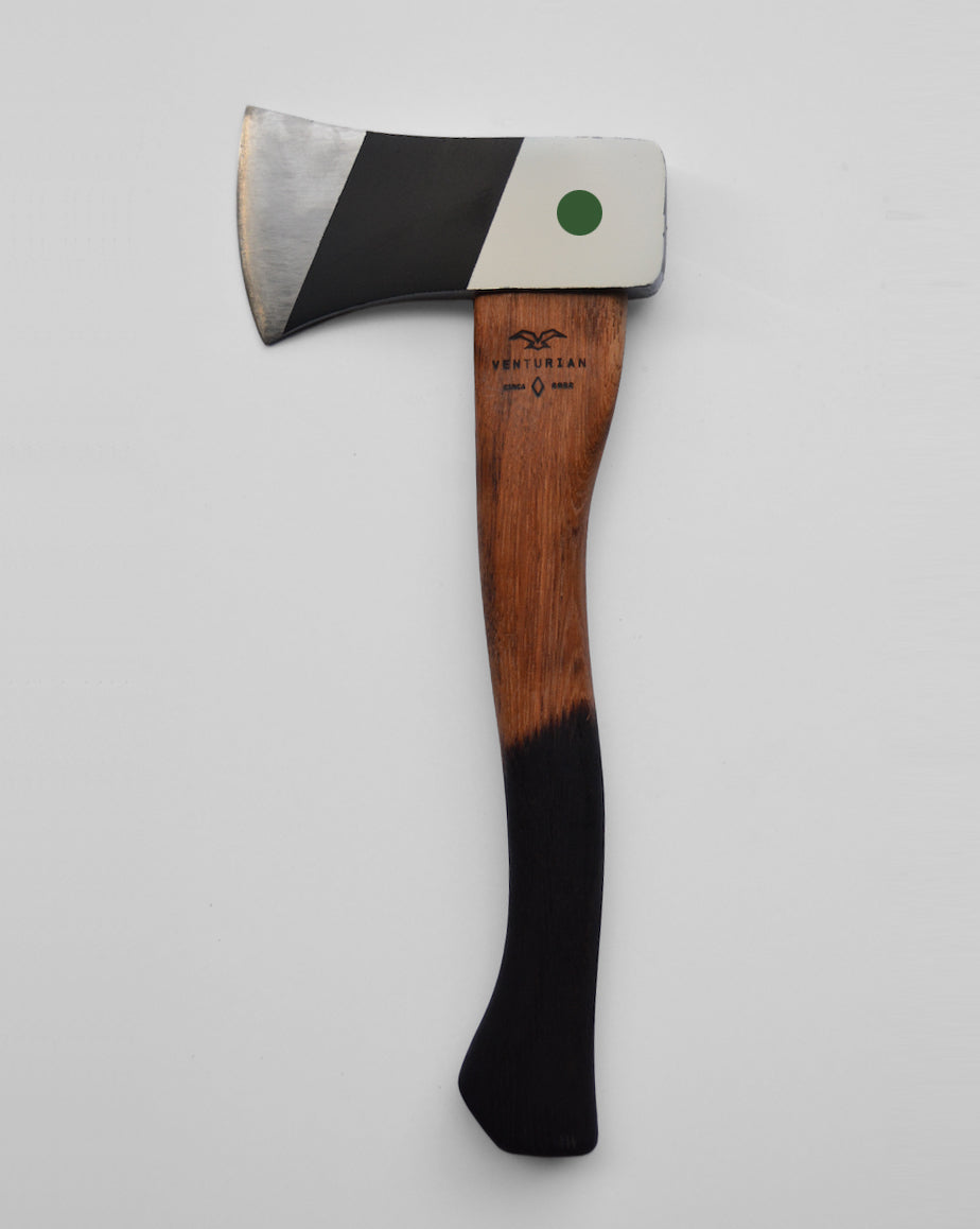 An hand painted camp axe with black and white angles and a green dot. 