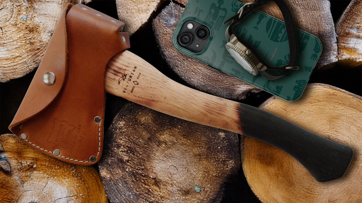 Axes with leather sheaths and a phone case on wooden logs