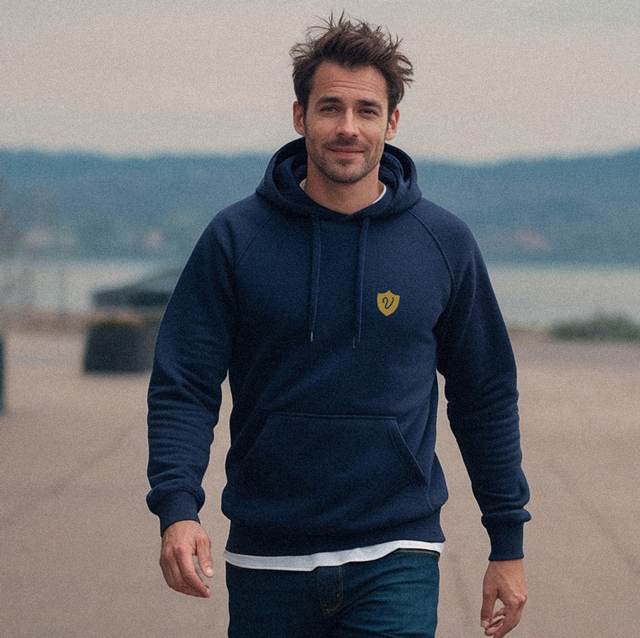 Man wearing a navy blue hoodie with a yellow logo outdoors