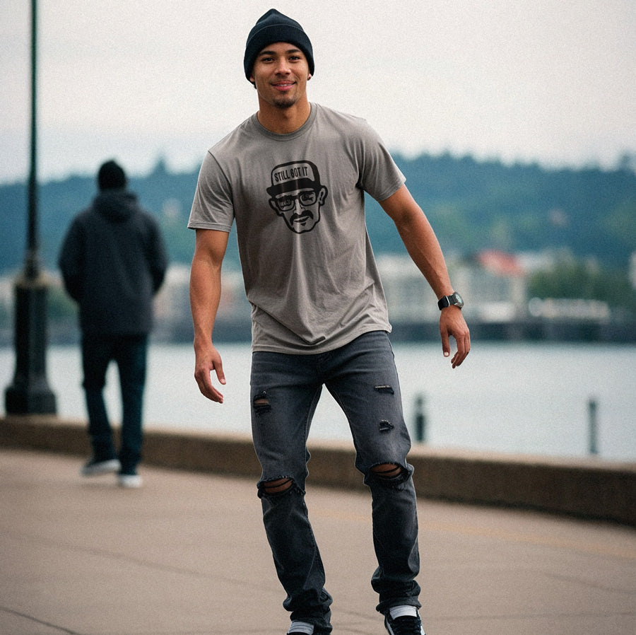 Man wearing a graphic t-shirt and beanie walking along a waterfront path.