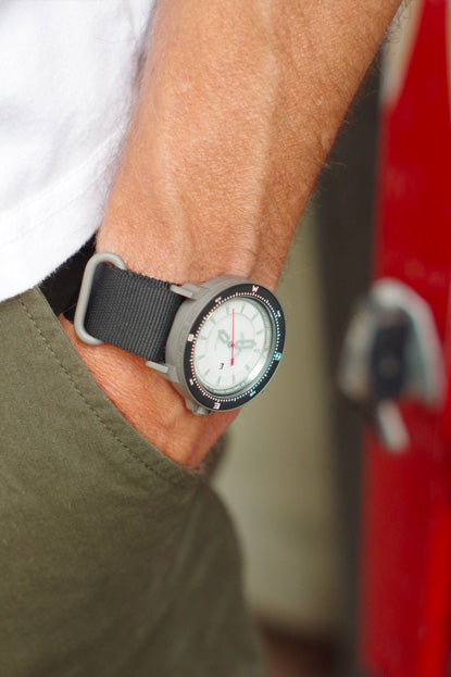 Person wearing a watch with a black strap on a blurred background