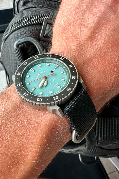 Close-up of a wrist wearing a watch with a robin's egg blue dial and black strap.