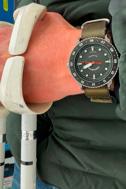 Person holding skis and ski poles with a watch on their wrist